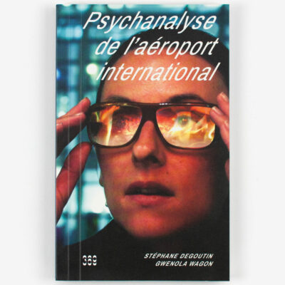 Couverture de Psychanalyse de l'aéroport international. Le portrait d'un homme avec des lunettes, le reflet révèle des flammes.